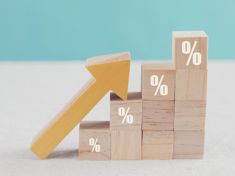 Wooden blocks with percentage sign and arrow up demonstrating increase in interest rates 