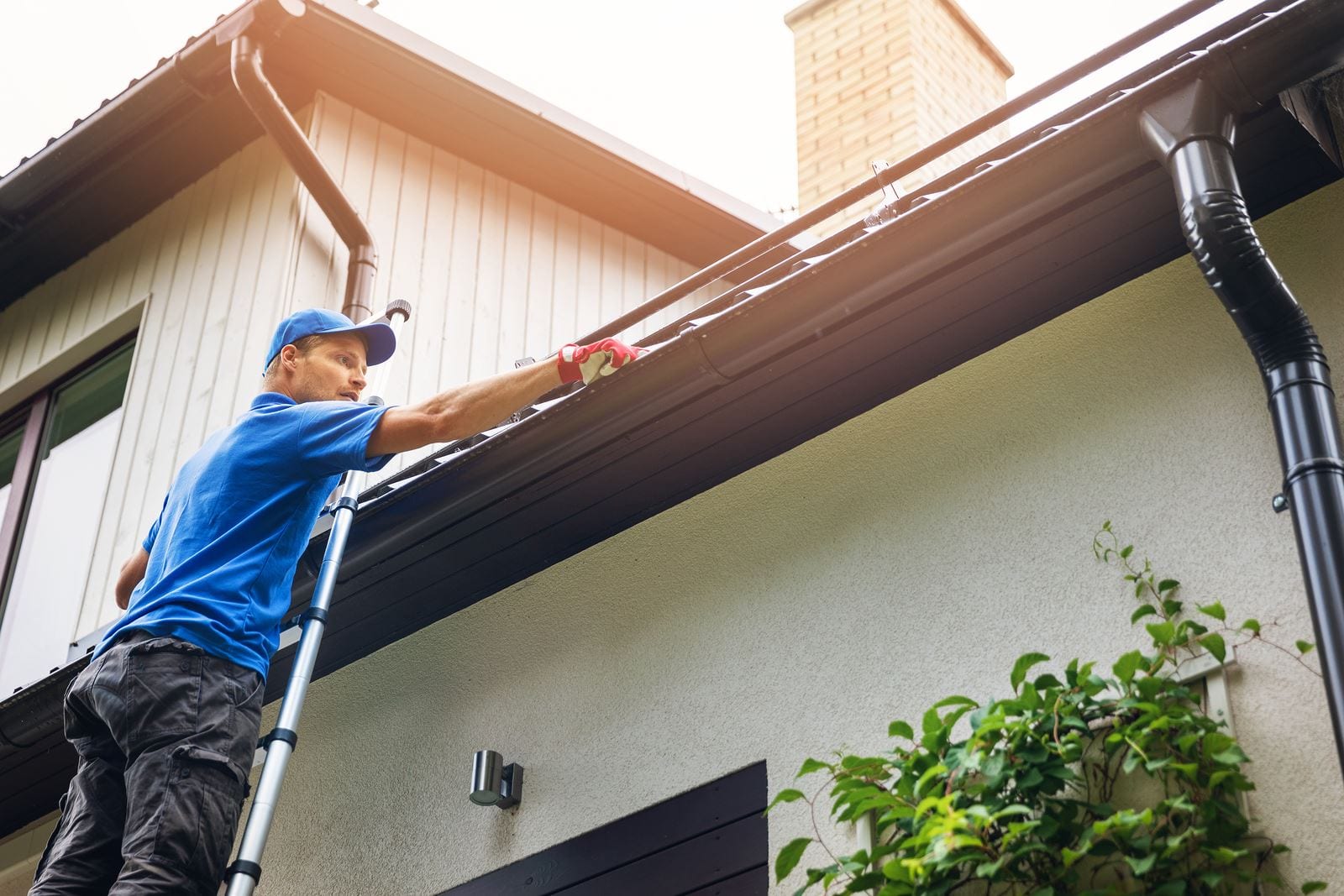 BC landlord cleaning house gutters on a ladder and completing annual property maintenance